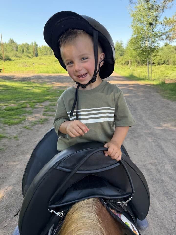 A grinning child on a pony on the farm road at Full Circle Vaulting